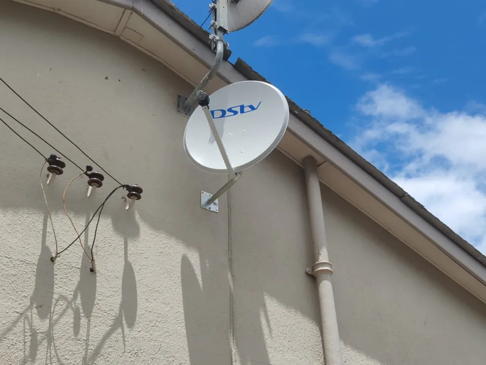 Satellite dish mounted on a roof with its bracket and cabling