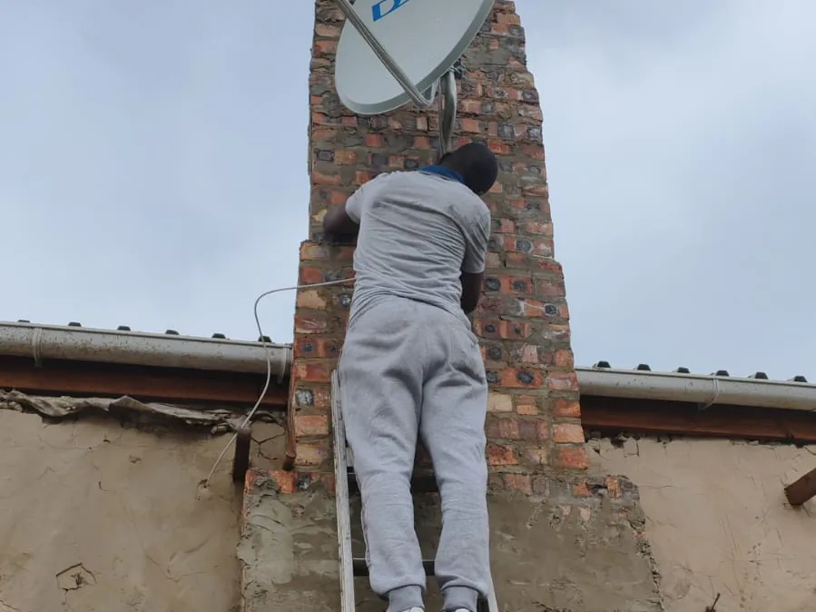 Technician working at height on a satellite dish installation