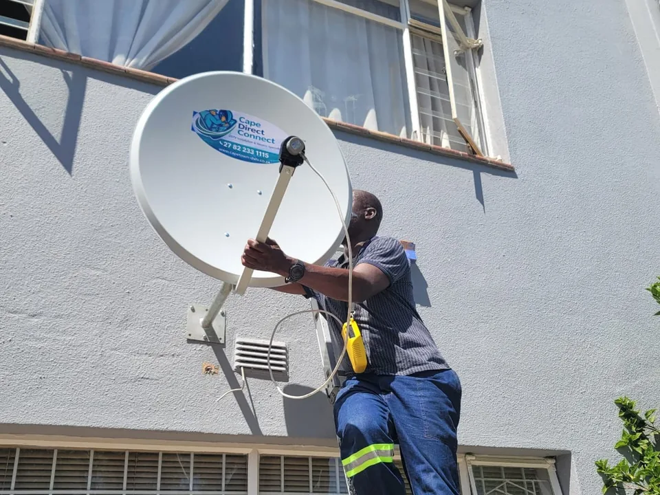 Technician working at height on a satellite dish installation